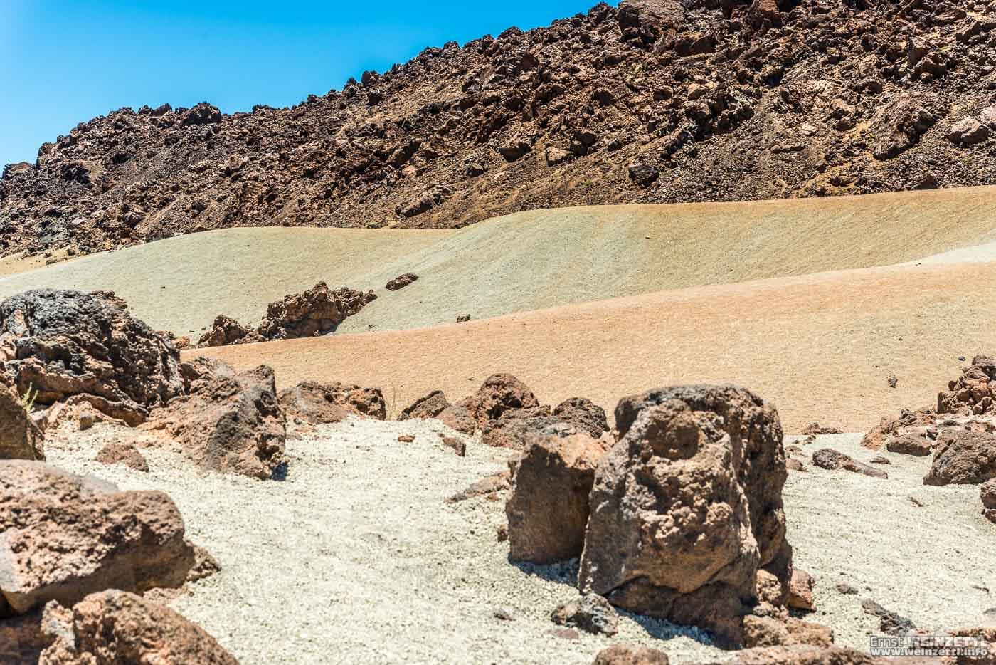 Verschiedenfarbige Sanddünen neben- und hintereinander.