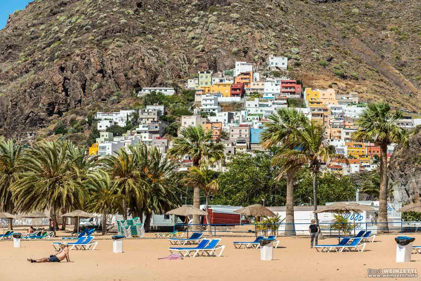 Hinter dem Strand und seinen Parkplätzen klebt ein Dorf im Felsen.