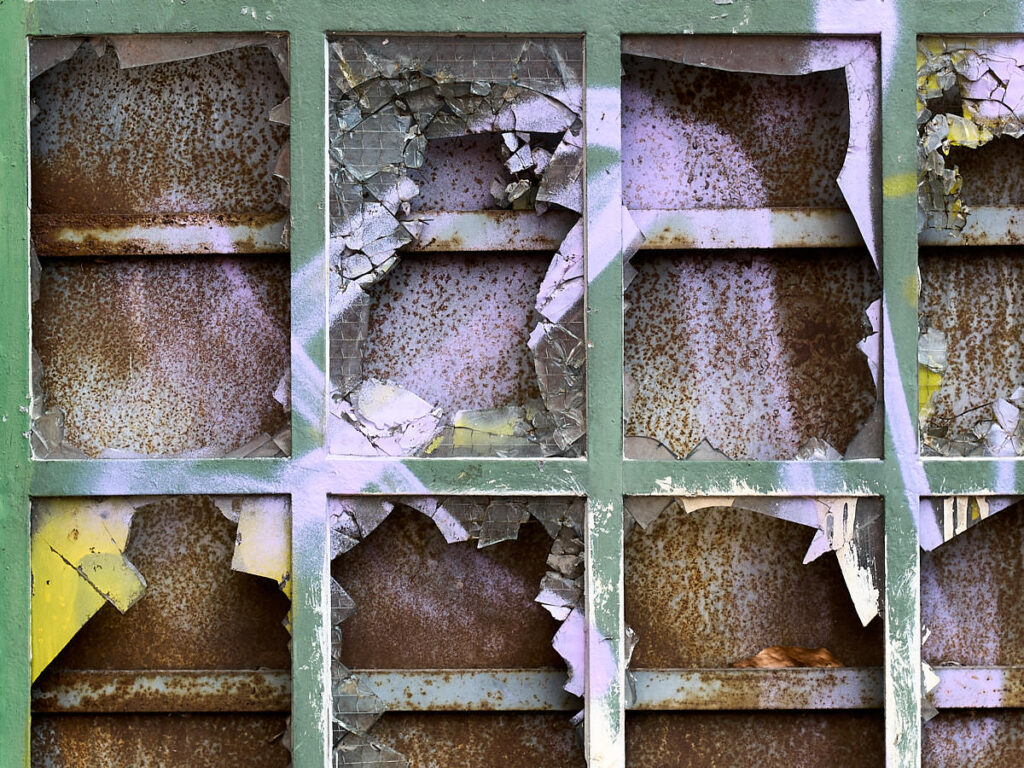 Ein zerbrochenes und bespraytes Gitterfenster