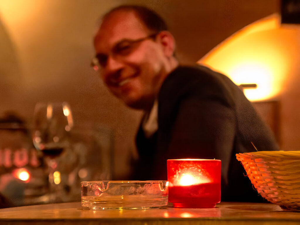 Ein Lokalgast mit Kerze und Aschenbecher