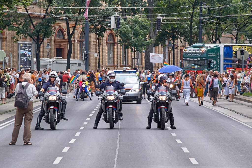Polizisten auf Motorrädern und Bereitschaftswagen vor einem Demonstrationszug