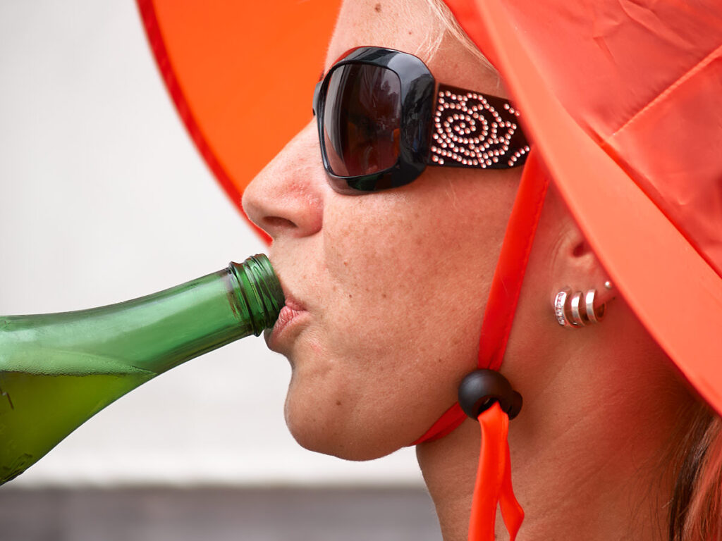 Eine Frau mit rotem Hut trinkt aus einer Flasche.