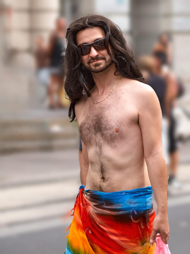Ein Mann mit nacktem Oberkörper und regenbogenfarbigem Rock