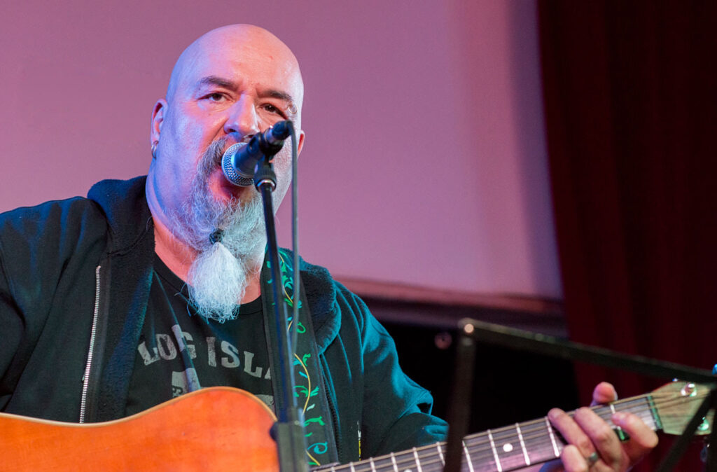 Ein Mann mit Gitarre singt in ein Mikrofon.