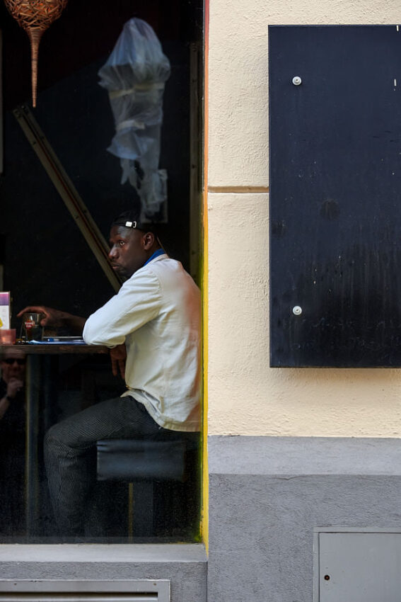 Ein Gast sitzt in einem Lokal hinter einem Fenster.