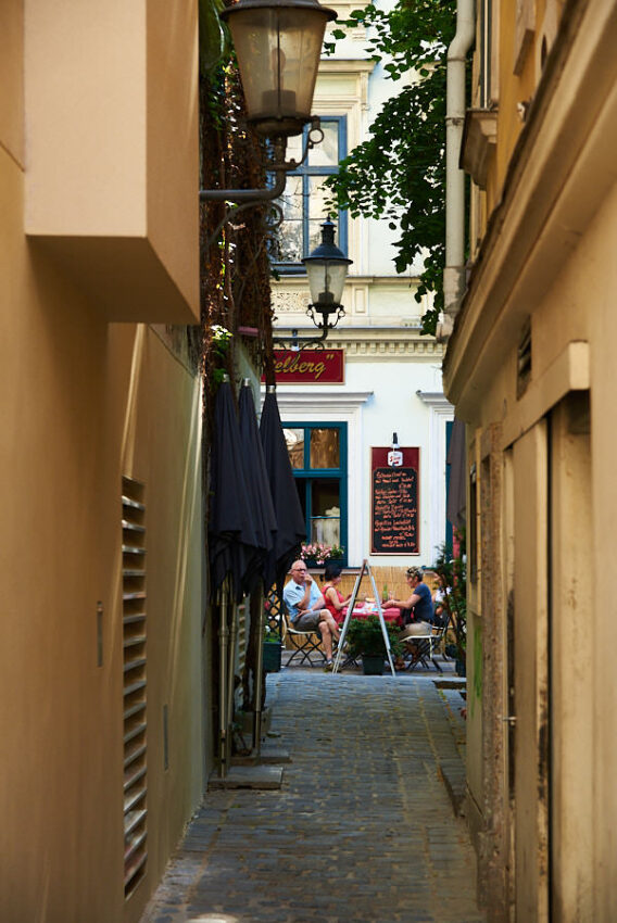 Blick durch eine enge Gasse auf ein Lokal mit Besuchern