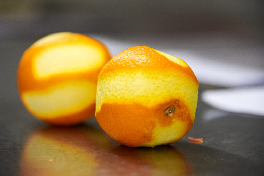 Zwei Orangen, von denen die Schalte abgeraspelt wurde