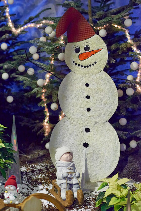 Ein Schneemann aus Kunststoffkugeln mit einem kleinen Kunststoffkind davor