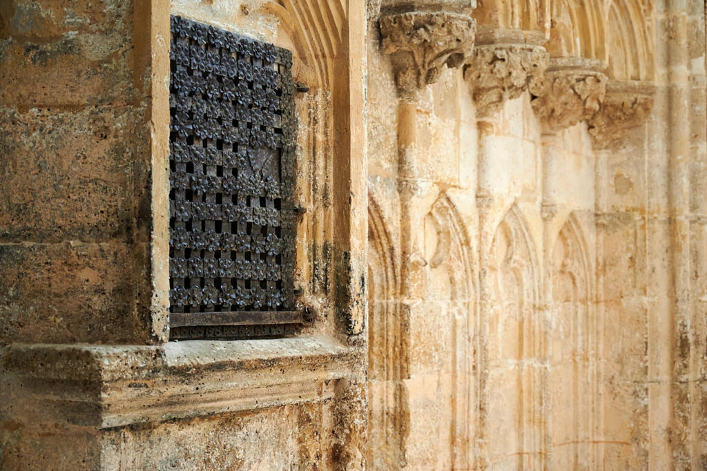 a window with a metal grate on a stone wall