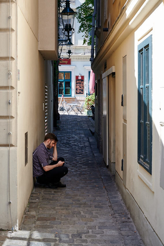 Ein Mann hockt in einer schmalen Gasse
