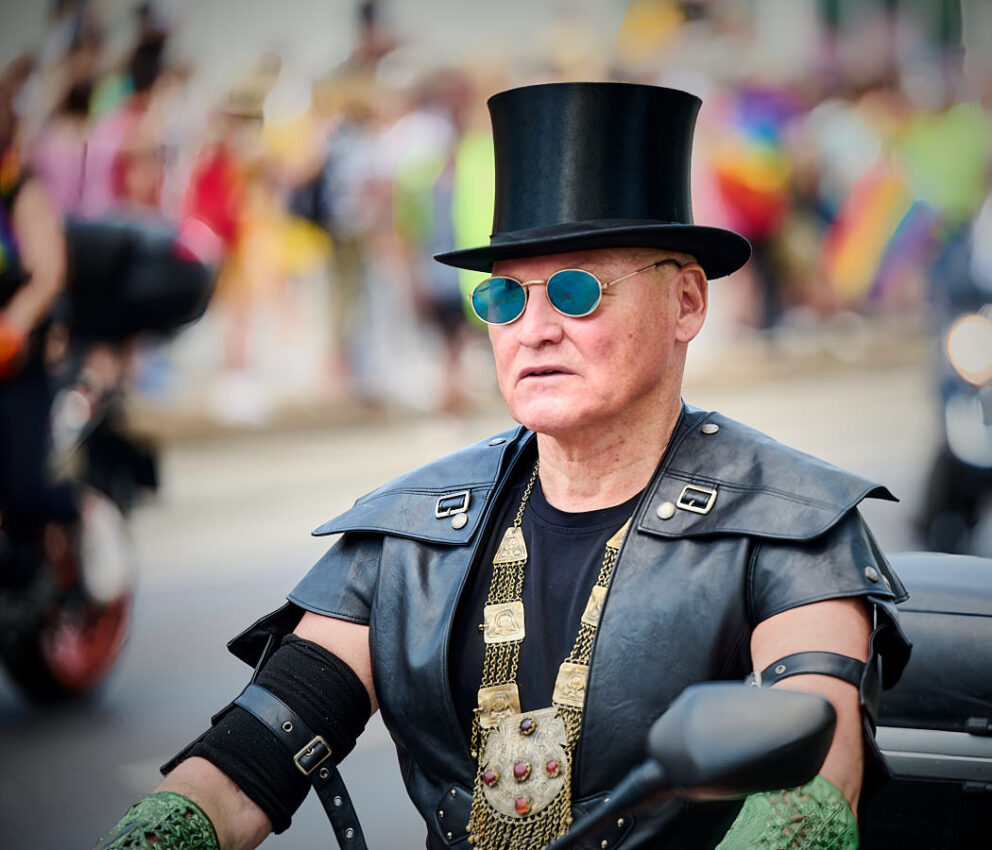 Mann mit schwarzer Kleidung und Zylinder auf einem Motorrad