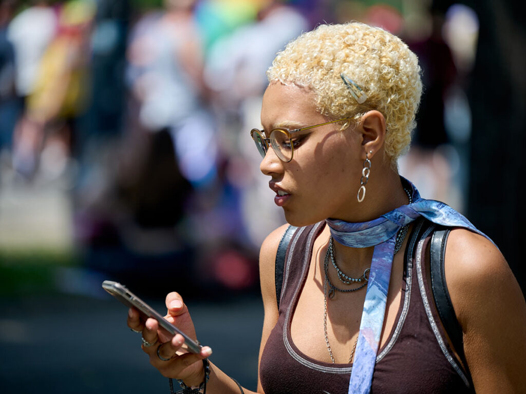 Frau mit blonden Haaren und Blick aufs Handy
