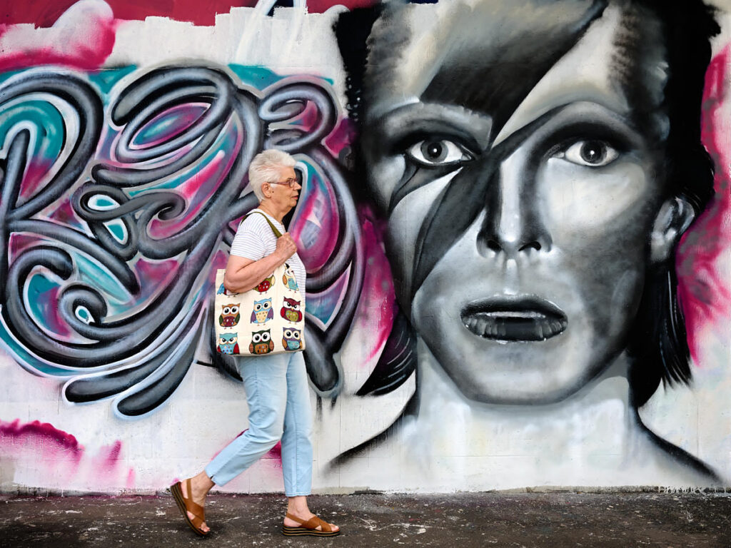 Eine Frau vor dem Graffiti-Gesicht David Bowies